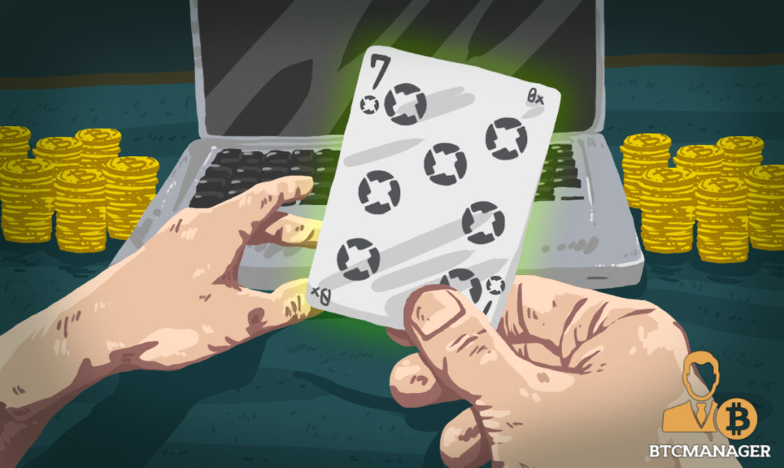 Person Holding an 0x-Branded Playing Card Sitting in Front of their Laptop